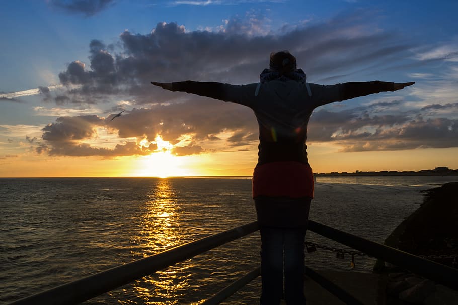 person opening arms while standing on corner of ship during golden hour HD wallpaper