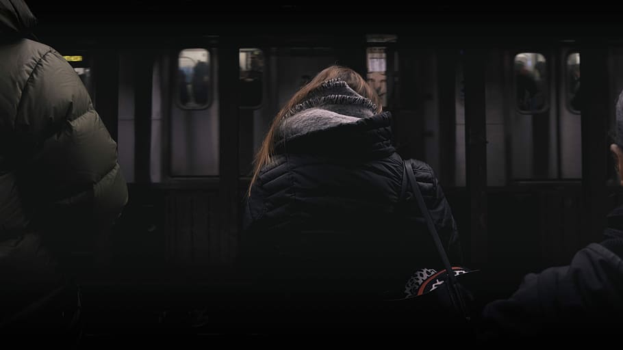 person in black coat standing in front of white panel door, woman sitting in front of train station HD wallpaper