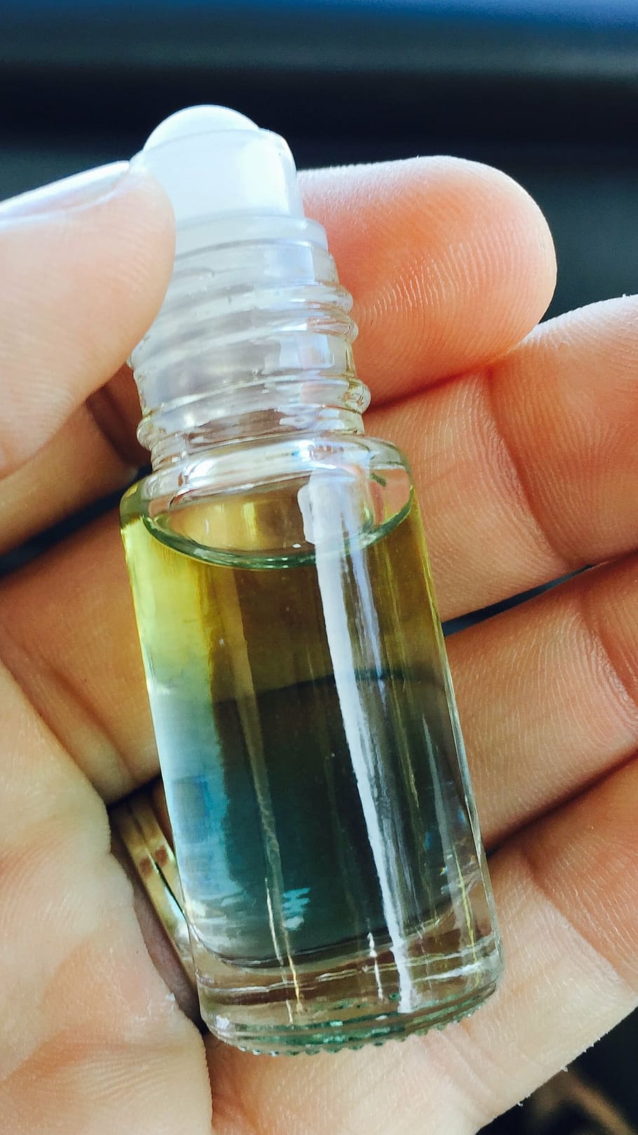 person holding clear glass mini roll-on bottle, essential oils HD wallpaper