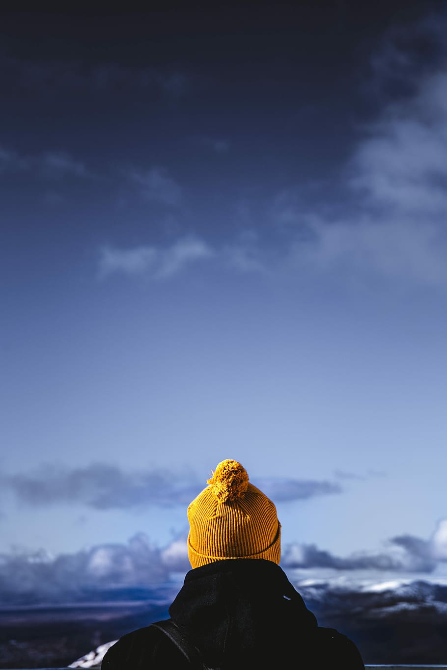 person wearing brown bobble hat facing cloudy skies, man wearing yellow bobble hat and black jacket HD wallpaper