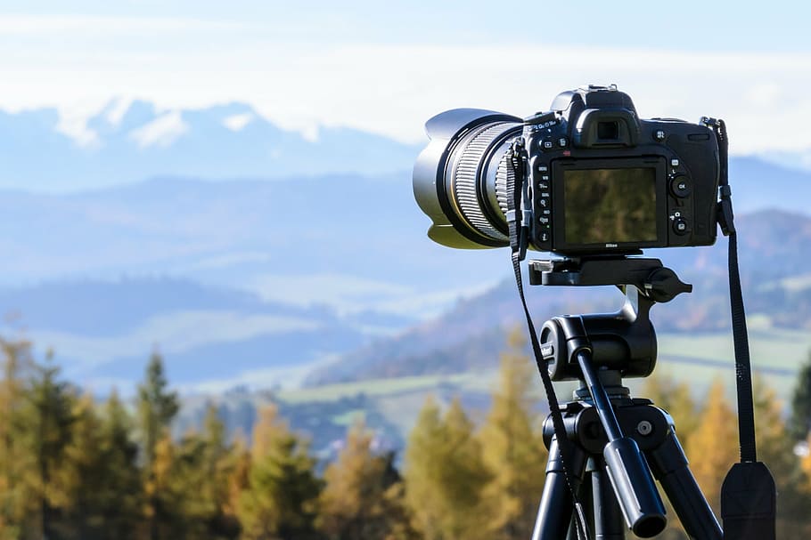 black DSLR camera in black tripod taking shot of mountains during daytime