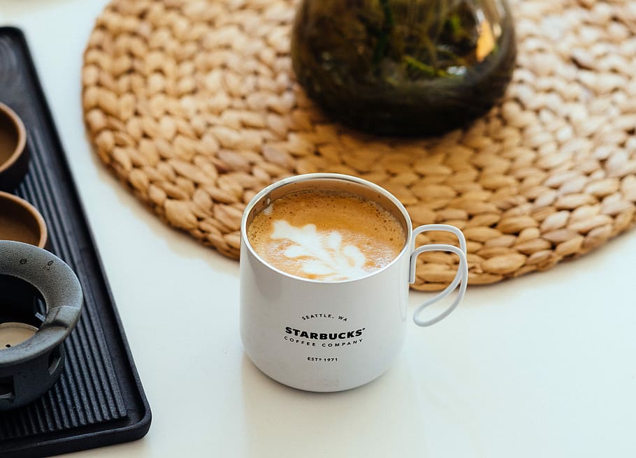 cappuccino in white starbucks mug, white Starbucks mug filled with coffee beside black serving tray