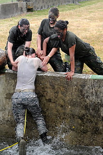 woman in type-B army uniform being pulled-up over water by three women HD wallpaper