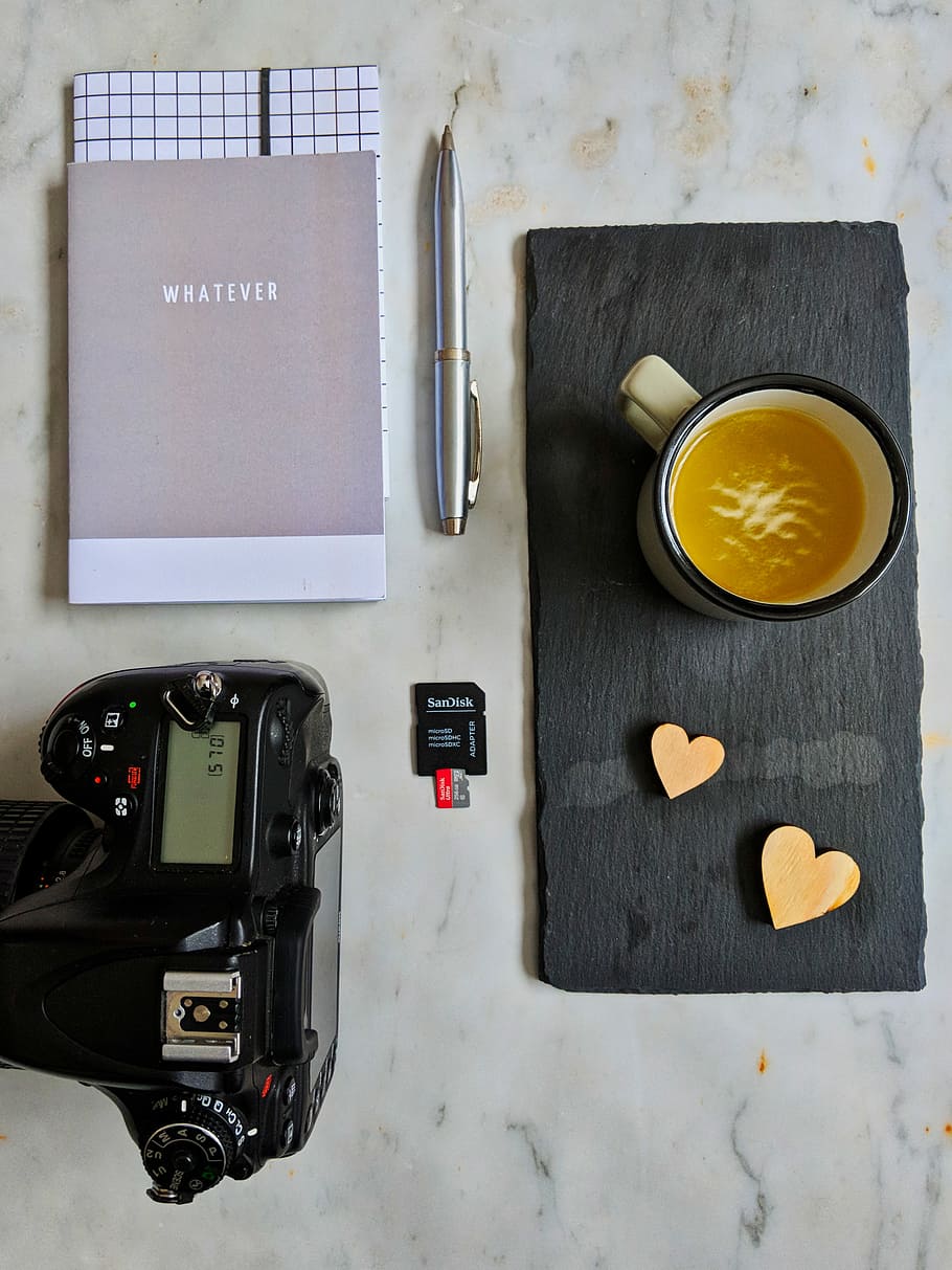 black DSLR camera near black SanDisk memory card and gray Whatever book HD wallpaper