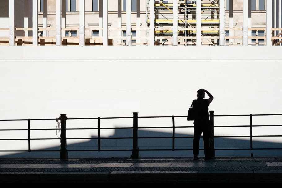 person standing near fence watching white wall, person standing in front street balustrade HD wallpaper
