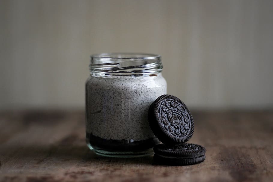 Oreo cookie and glass bottle, shallow focus photography of two chocolate biscuits leaning on clear glass bottle HD wallpaper