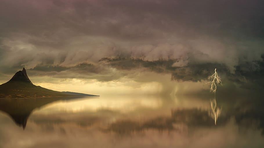 brown island surrounded by still body of water under clouds HD wallpaper
