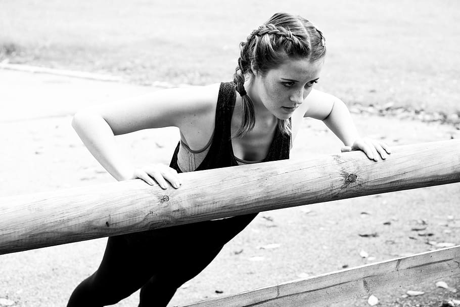 grayscale photo of woman wearing black shirt and pants doing push-up