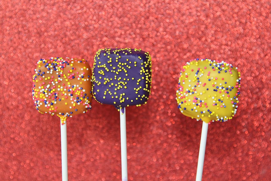 three assorted-flavor lollipops, purple, yellow, orange, cake HD wallpaper