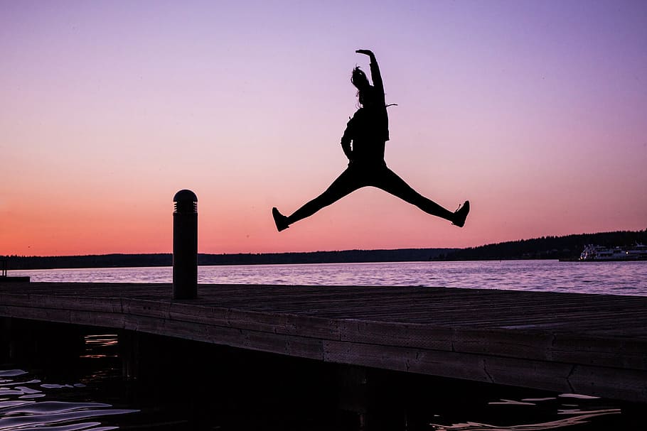 Silhouette of woman jumping on the coast at sunset, people, adventure