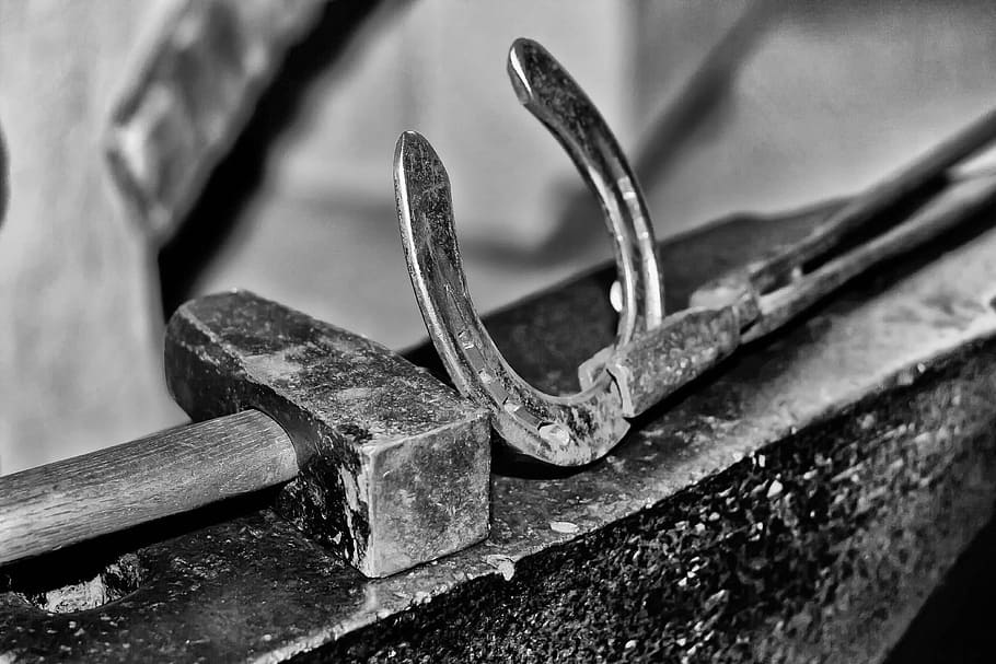 selective focus photography of horseshoe and hammer, glow, blacksmith