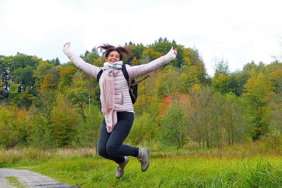 woman wearing jacket and blue denim jeans jumping, hop, air jump