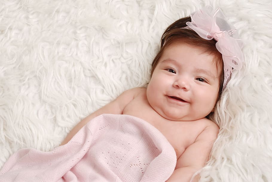 close up photo of baby lying on white textile, pink, headband