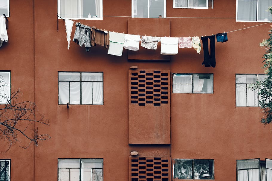 clothes hanging during daytime, brown concrete building, apartment building