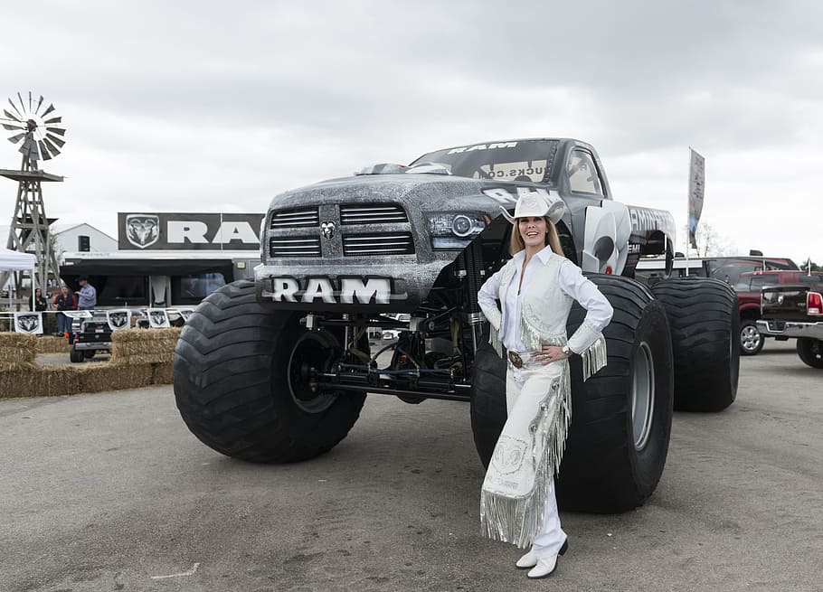 smiling woman standing in front of black Dodge Ram 1500 single cab pickup truck at daytime