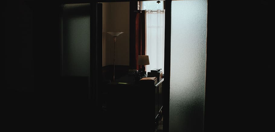 Dark hallway leading to office with desk and lamp, white torchiere floor lamp HD wallpaper