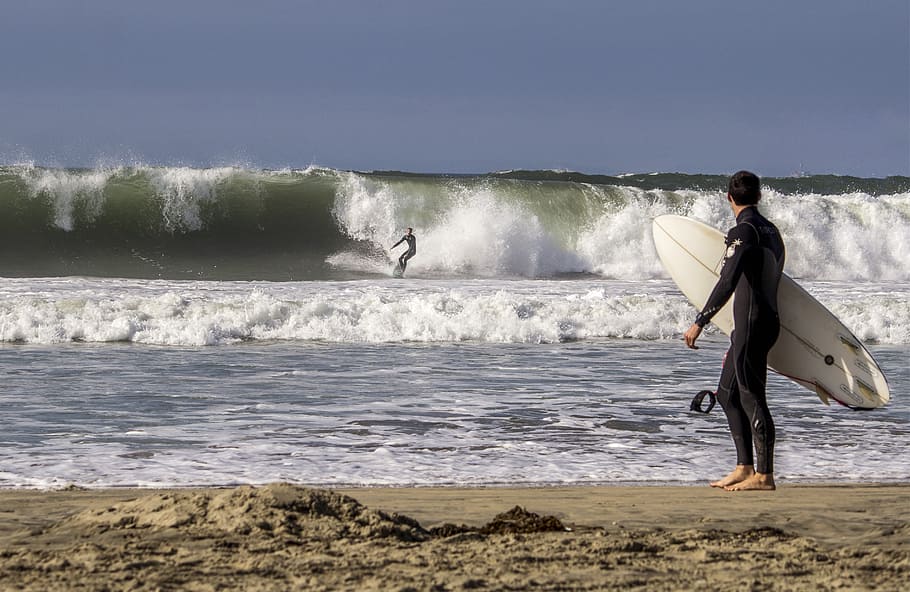 person standing beside seashore holding surfboard, waves, ocean HD wallpaper