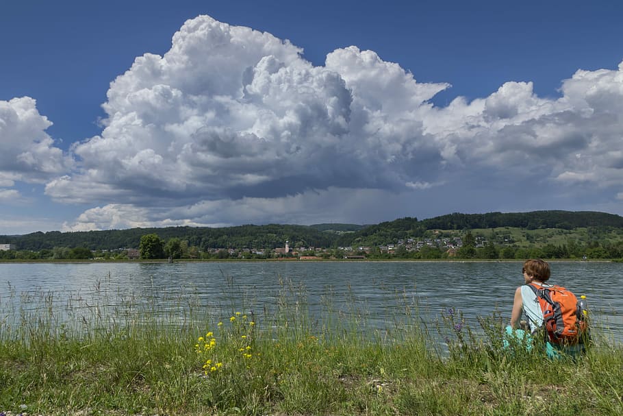 man sitting wearing backpack beside body of water, hiking, thunderstorm HD wallpaper