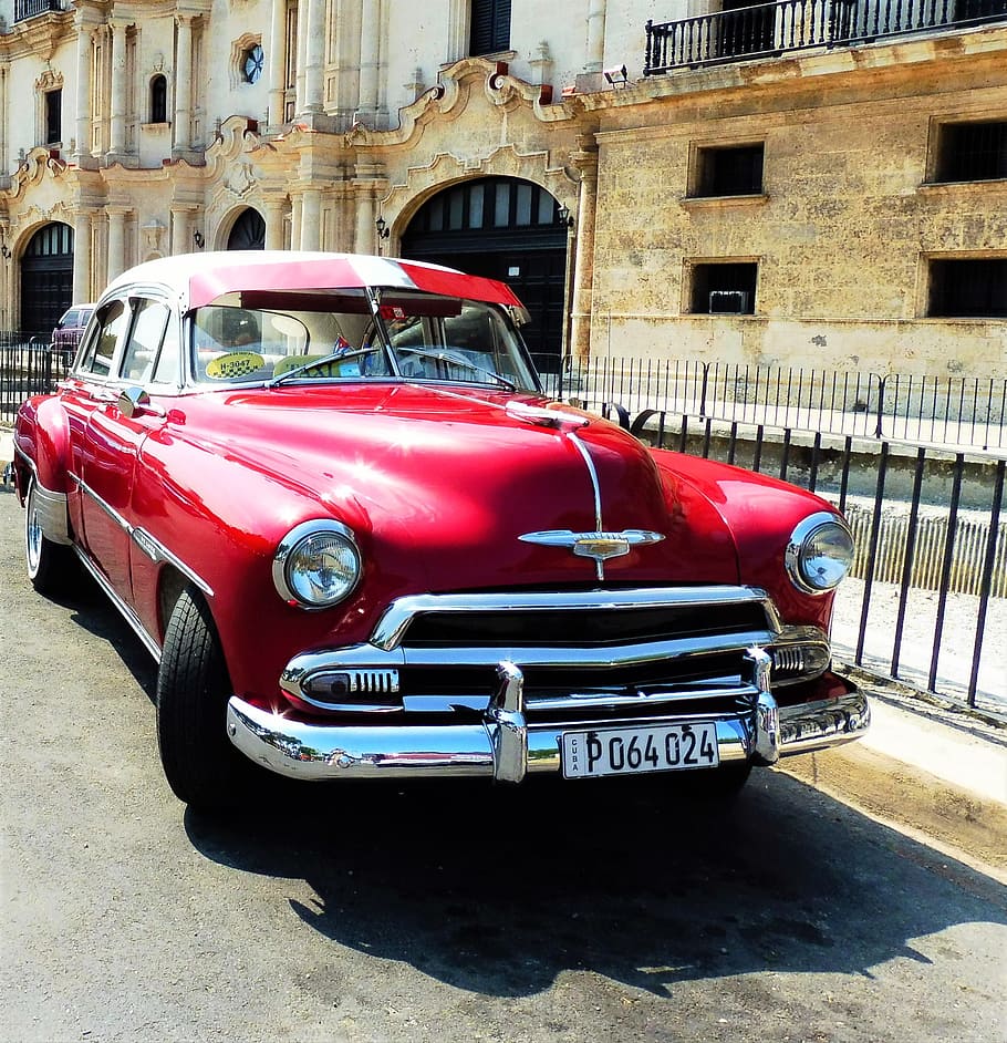 classic red sedan parked on roadside near black fence, Havana, Cuba
