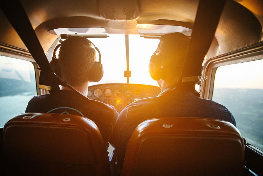 two men piloting plane during daytime, two person wearing black headsets HD wallpaper