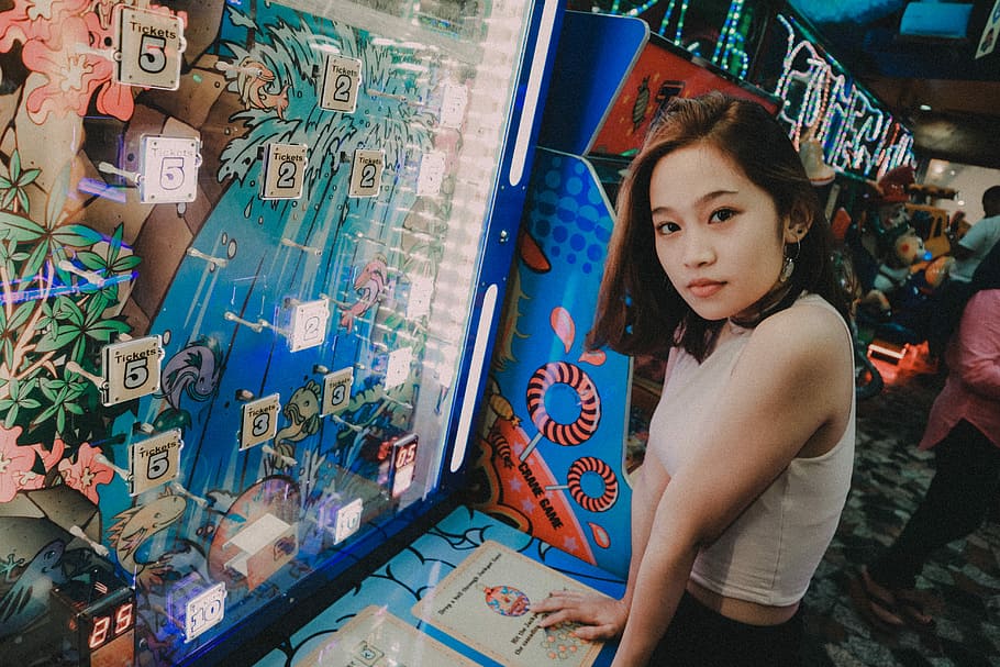 woman wearing white top standing in front on the blue slot machine, woman standing infront of blue and white counter, HD wallpaper