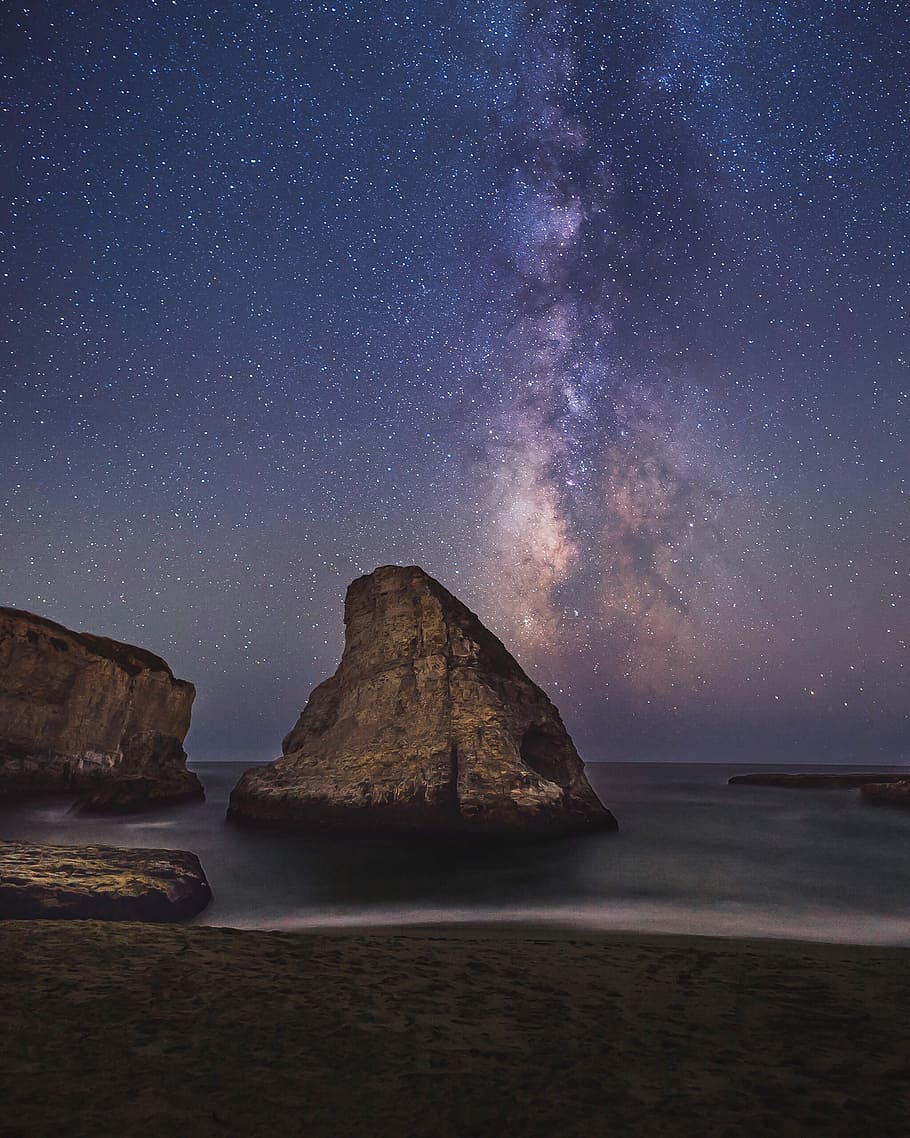 Galaxy photography, gray rock formation in sea under starry sky HD wallpaper