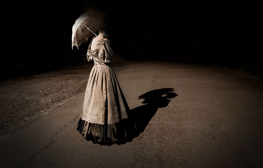 woman in gray dress holding umbrella while standing on concrete floor during nighttime HD wallpaper