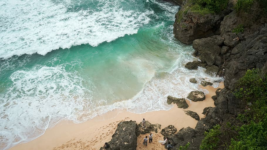 ocean waves on shore beside mountain, aerial photo of beach at daytime HD wallpaper