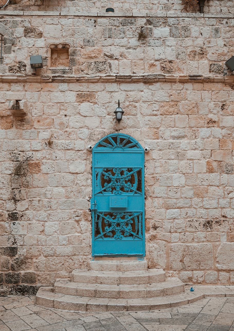 person showing blue wooden wall decor, blue metal door on grey brick building HD wallpaper
