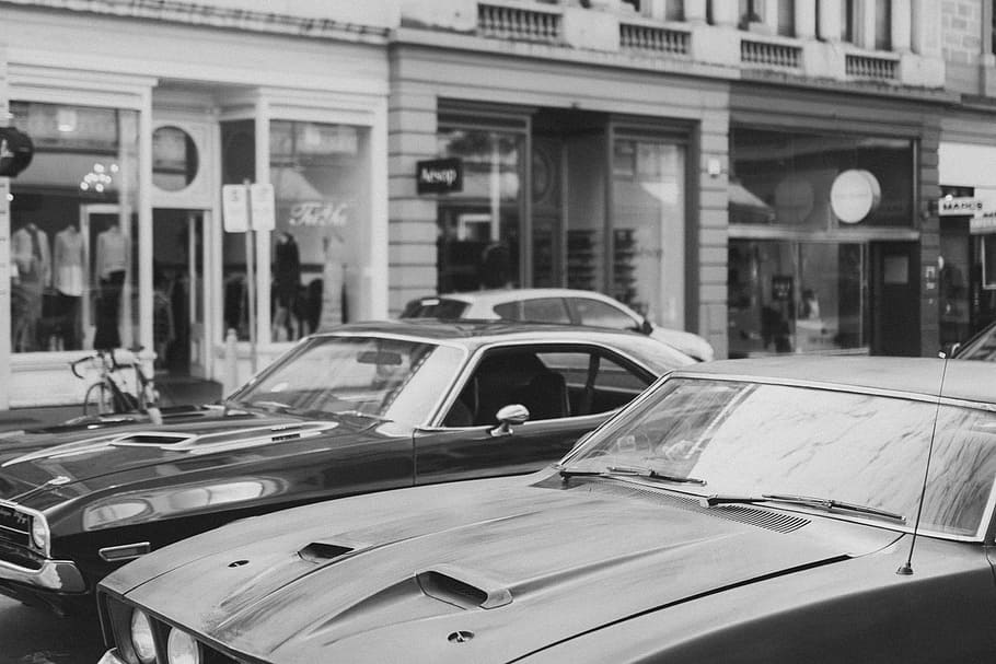 greyscale photography of cars on road beside buildings, car park near another car HD wallpaper
