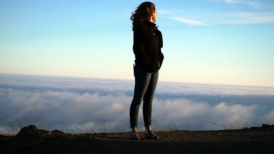 woman standing on hill while while facing white clouds during daytime, HD wallpaper