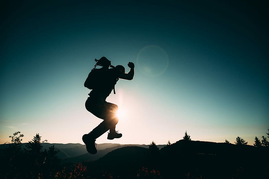 silhouette of jumping person on hill, silhouette of man jumps on top of mountain
