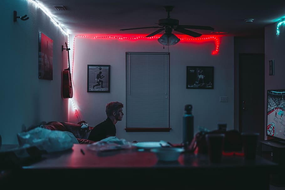 man sitting inside room near window blinds with lights turned on, photograph of man seating on sofa playing NBA HD wallpaper