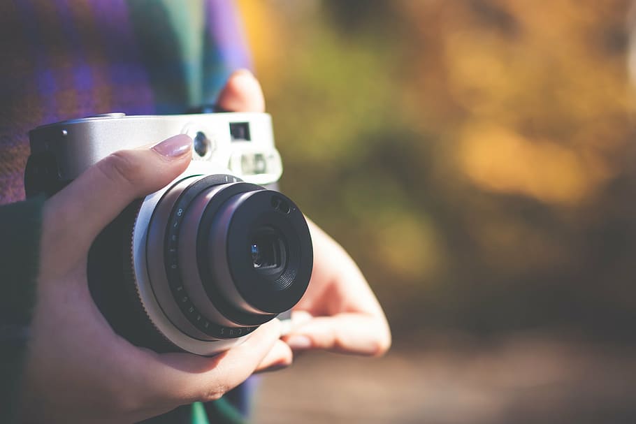 person holding white and black MILC, camera, lens, photographer HD wallpaper