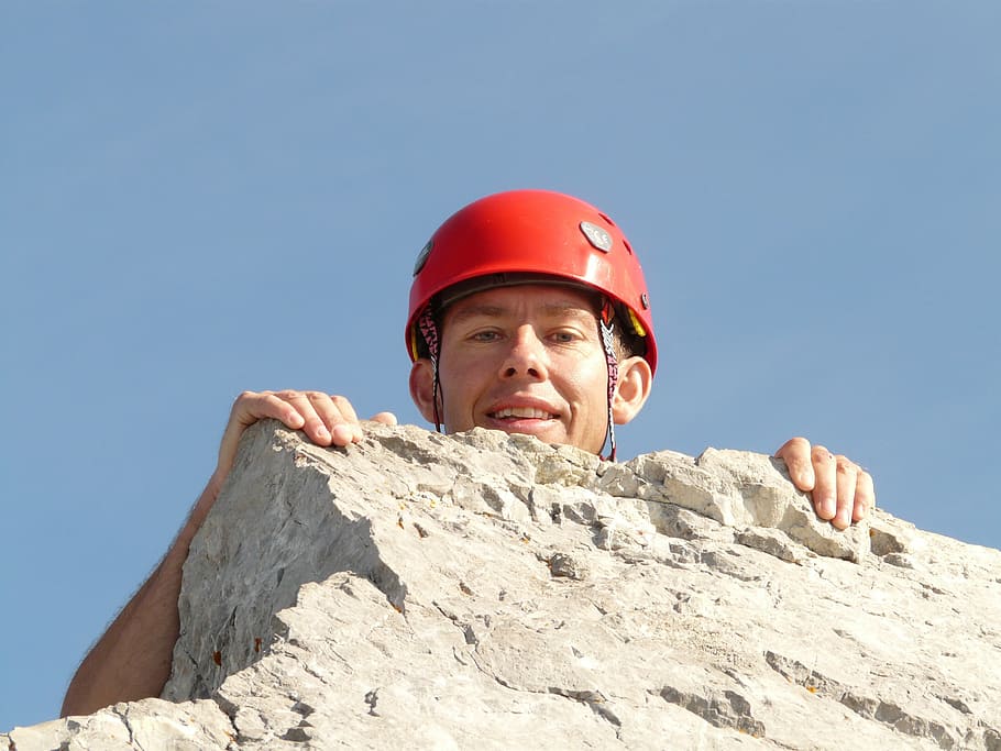 man with red hard hat on top of grey rock formation, summit stormer
