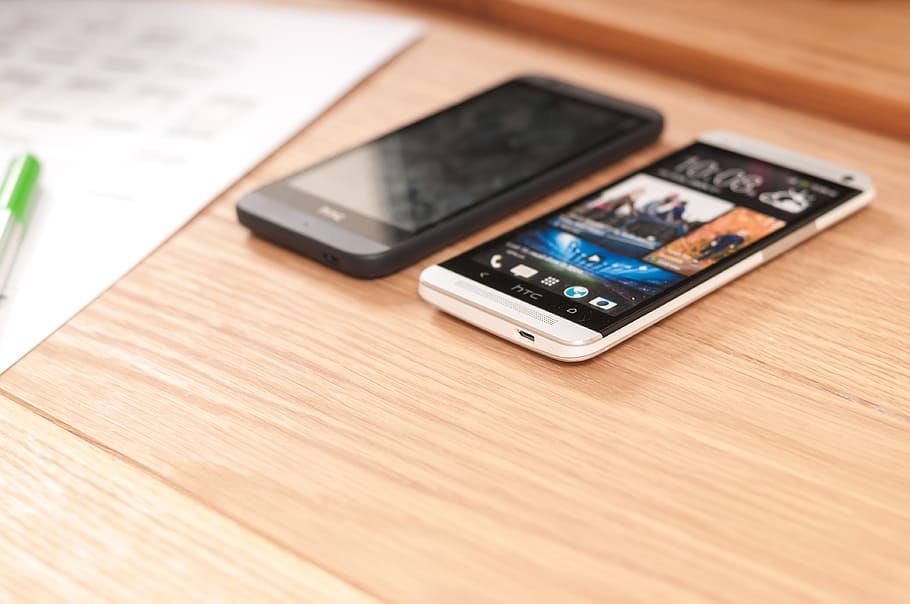 two black and white Android smartphone turned-on on brown wooden table HD wallpaper