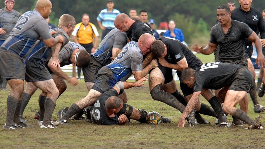 group of men playing rugby on mud field at daytime, football
