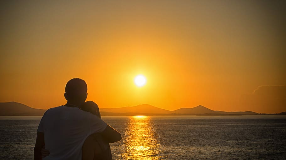 couple hugging near calm sea during golden hour, Man and woman