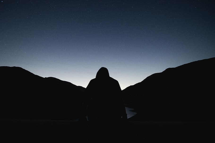 silhouette of a person facing sunrise, silhouette of man standing near dividen mountains and river