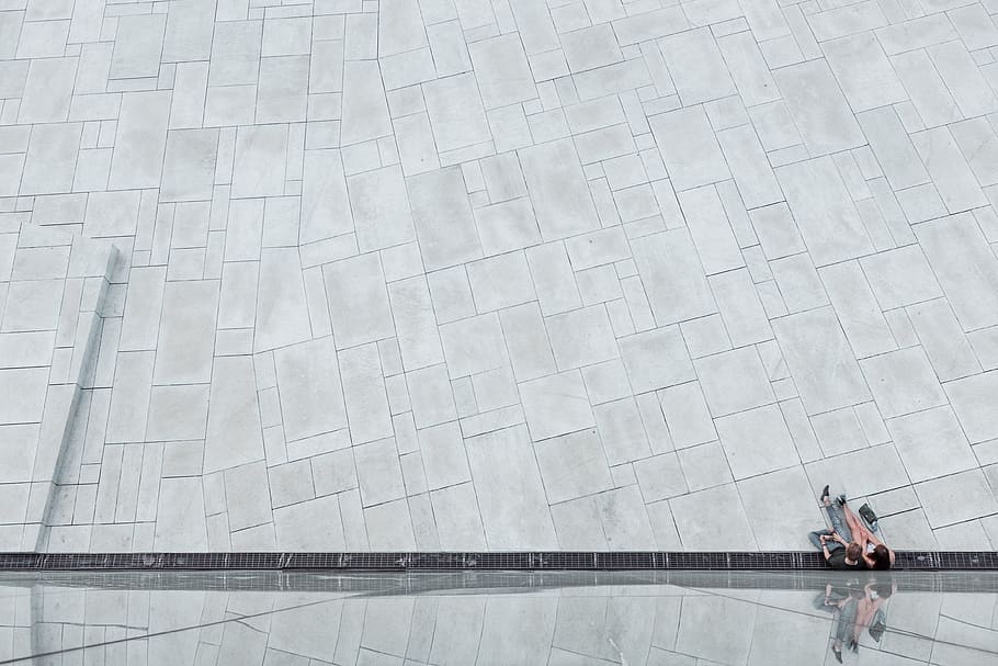 aerial photography of gray concrete flooring, two people sitting on gray concrete surface HD wallpaper
