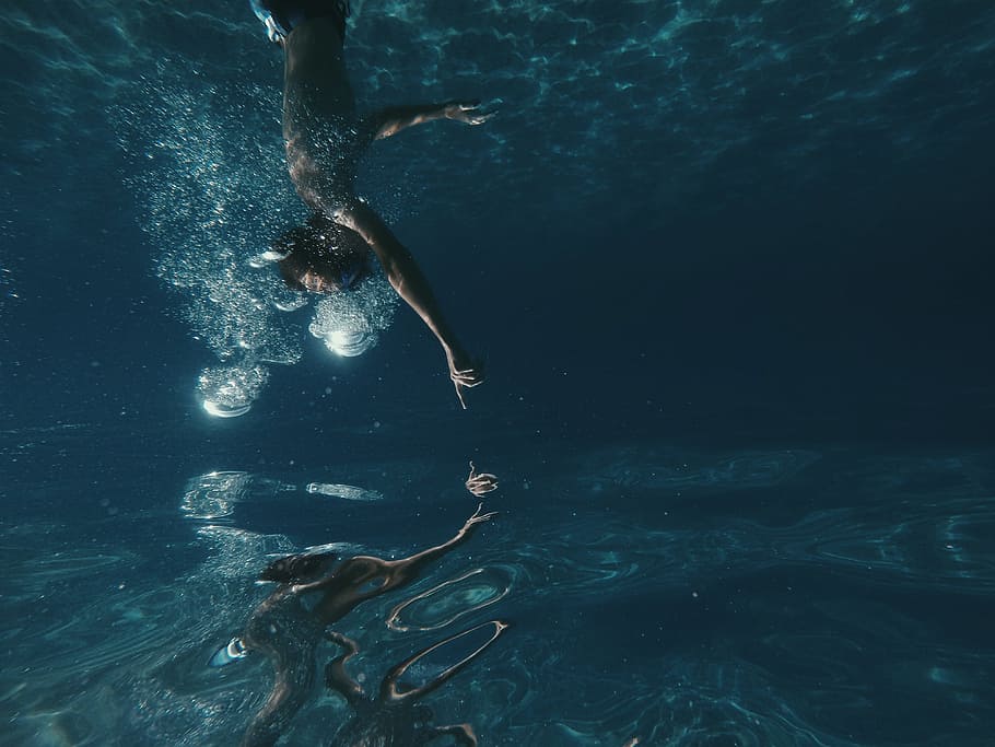 man swimming underwater, person diving in water, Close, reflection