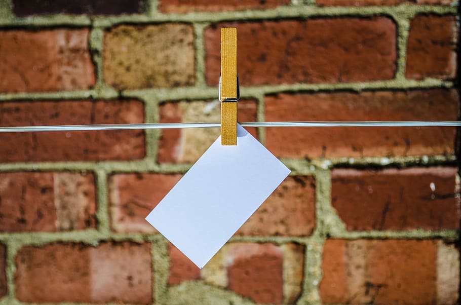 close up photo of white printing card hanging in rope, advertisement