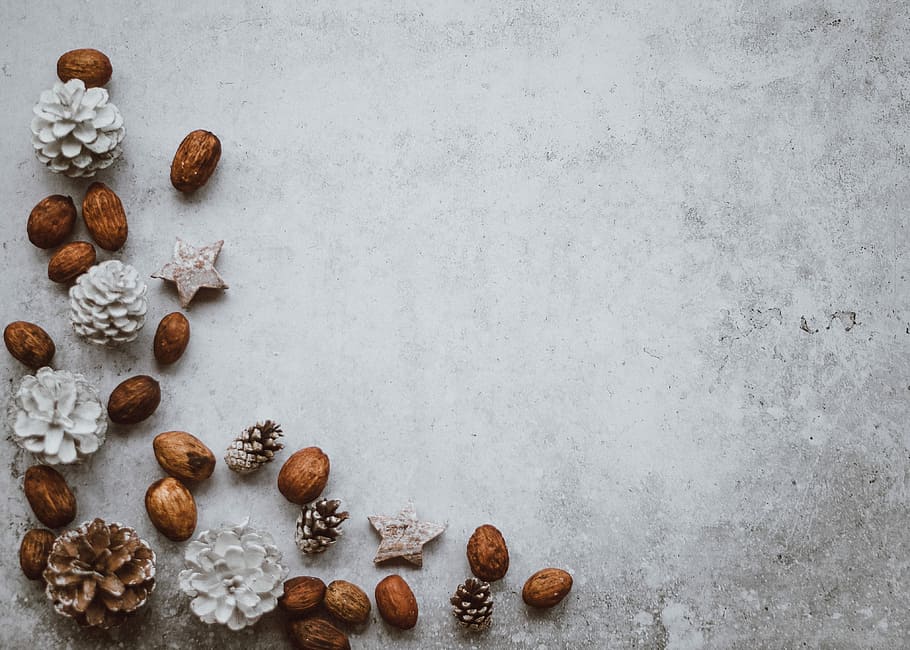 Christmas background, almond nuts on gray surface, stars, pine cone