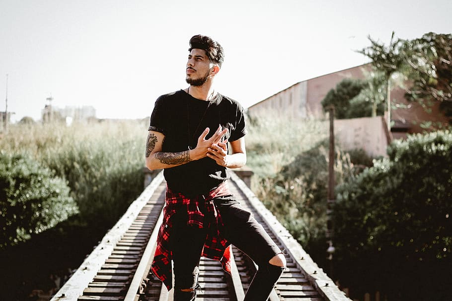 man standing on railroad near plants, man in railroad during daytime HD wallpaper