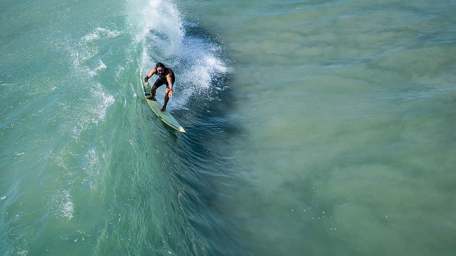 aerial photography of man surfing ocean wave during daytime HD wallpaper