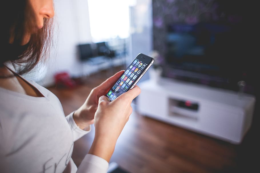 shallow focus photography of woman in v-neck long-sleeved top holding space gray iPhone 6 HD wallpaper