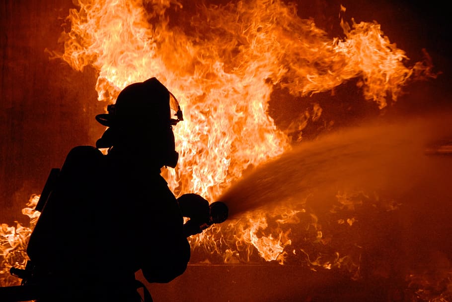 silhouette of fireman putting out fire