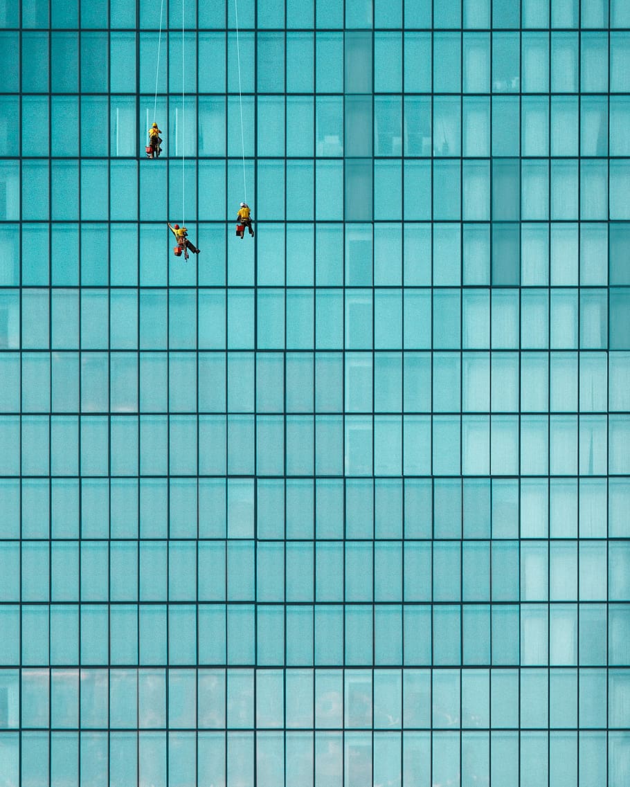 three men cleaning windows, three person hanging on clear glass building
