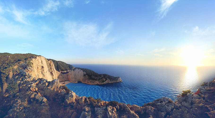 sea water surrounded by cliff, brown mountain near body of water during daytime HD wallpaper
