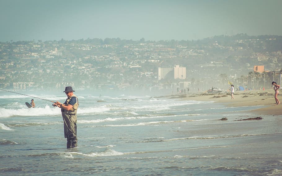 man in brown jumpsuit standing on beach while fishing, sea, people HD wallpaper